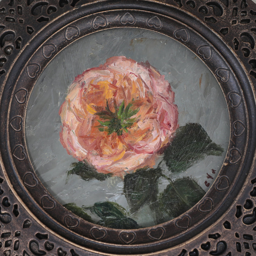 Close up of the Pink rose miniature oil painting in scalloped round frame on cream fabric