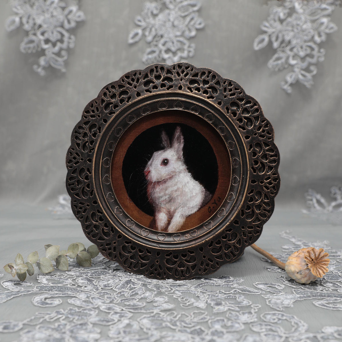 Framed white bunny print laid flat with dried rose and poppy pod