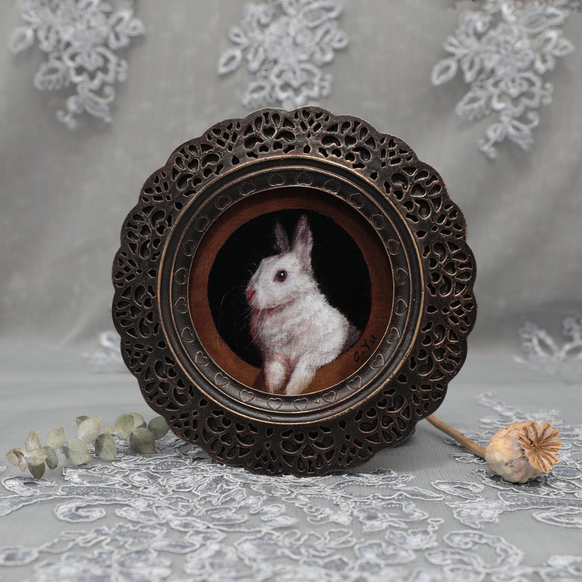 Framed white bunny print laid flat with dried rose and poppy pod