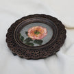 Overhead view of pink rose miniature painting in round openwork frame