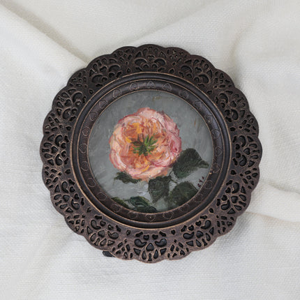 Pink rose miniature oil painting in scalloped round frame on cream fabric