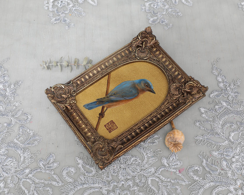 Overhead view of arch-frame bluebird art print with dried eucalyptus