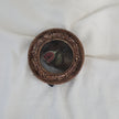 Overhead view of fig still life painting in round gilt frame, zoomed out, second angle