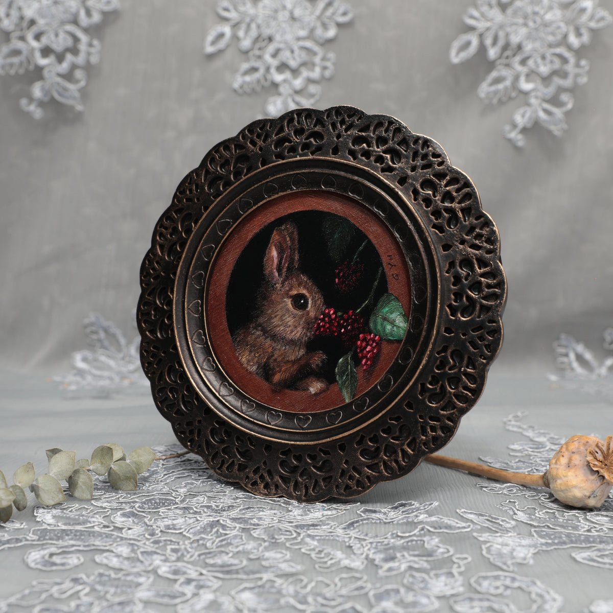 Framed bunny art print in ornate bronze frame standing, side view