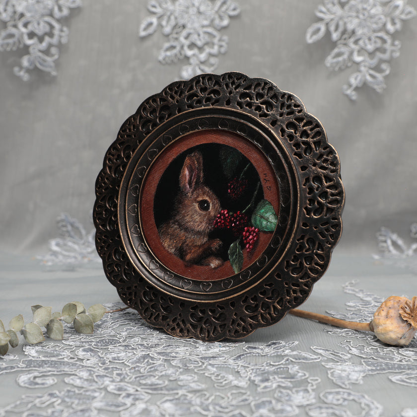 Framed bunny art print in ornate bronze frame standing, side view