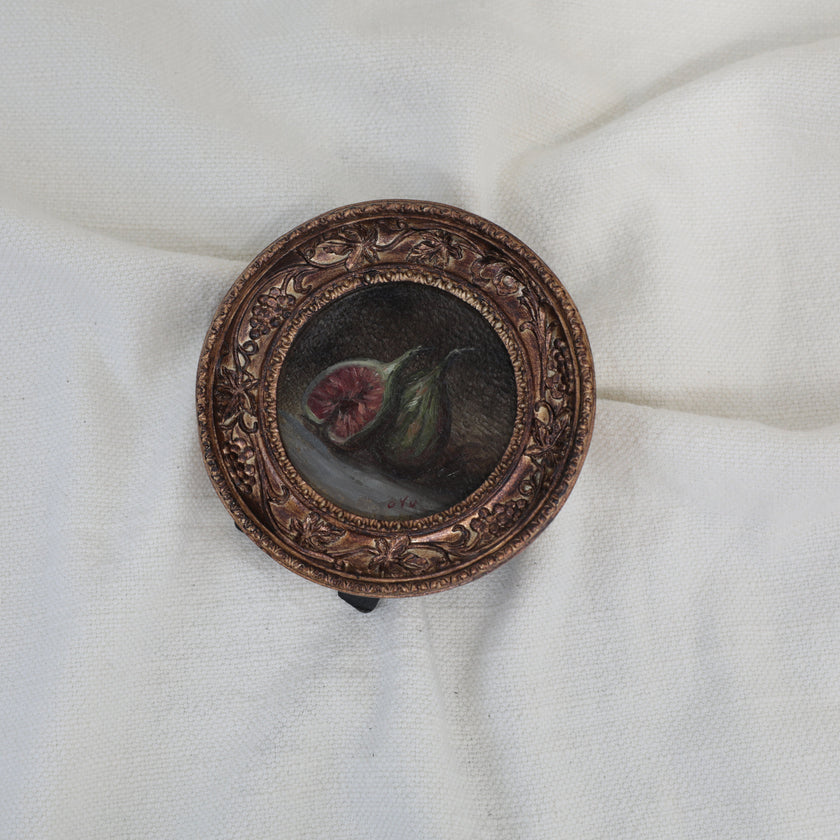 Overhead view of fig still life painting in round gilt frame, zoomed out, second angle