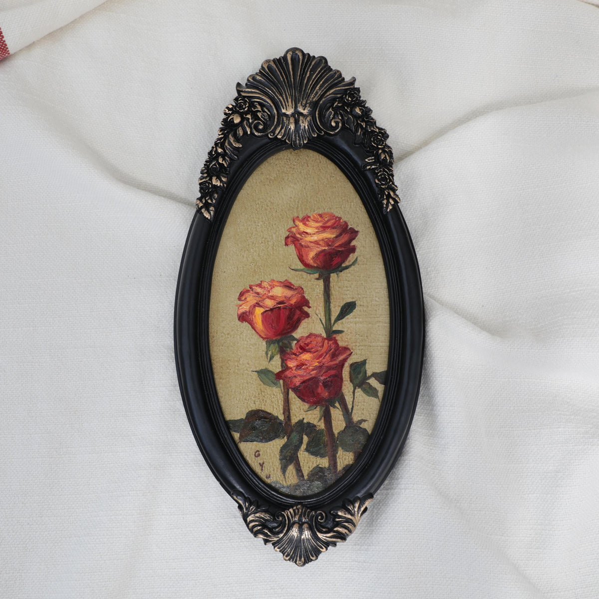 Original red roses oil painting in an ornate long oval gilt frame on cream linen