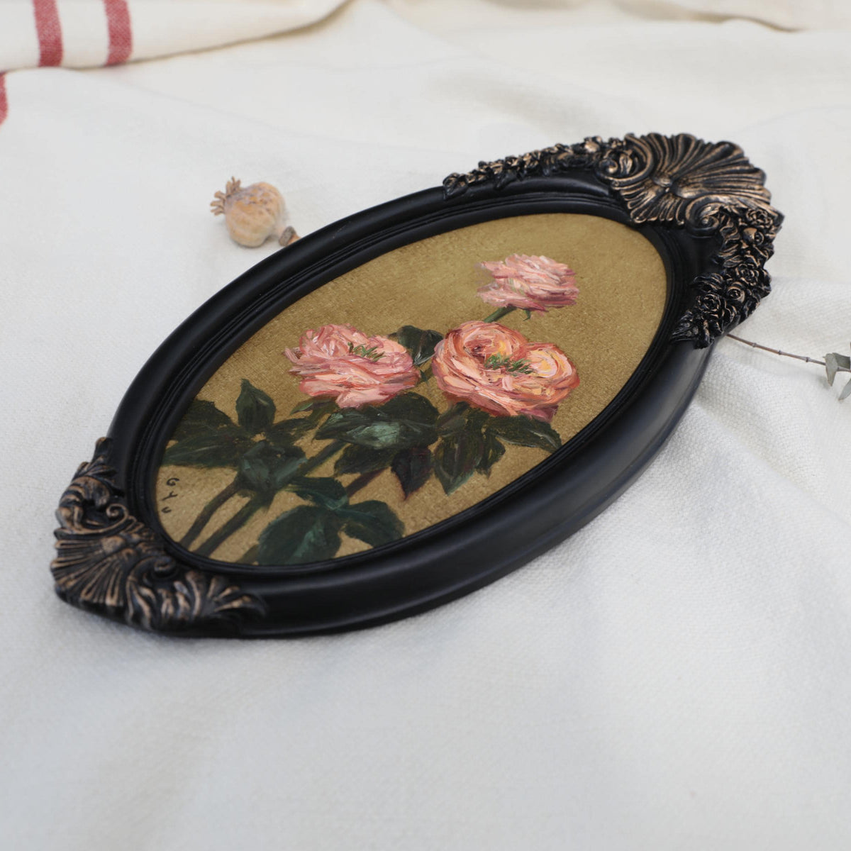 Original pink rose oil painting in an long oval gilt frame on cream line, side view