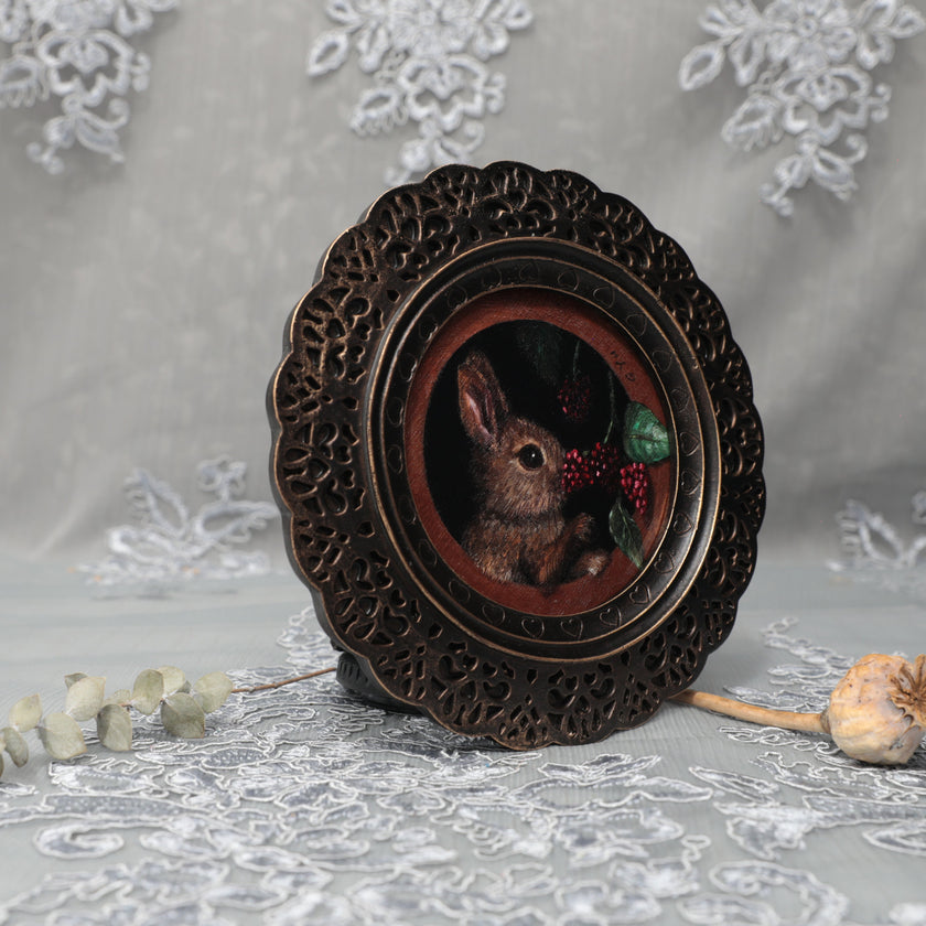Framed bunny art print in ornate bronze frame standing, side view