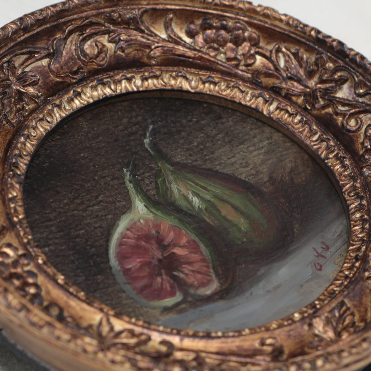 Close up side view of fig still life painting in round gilt frame