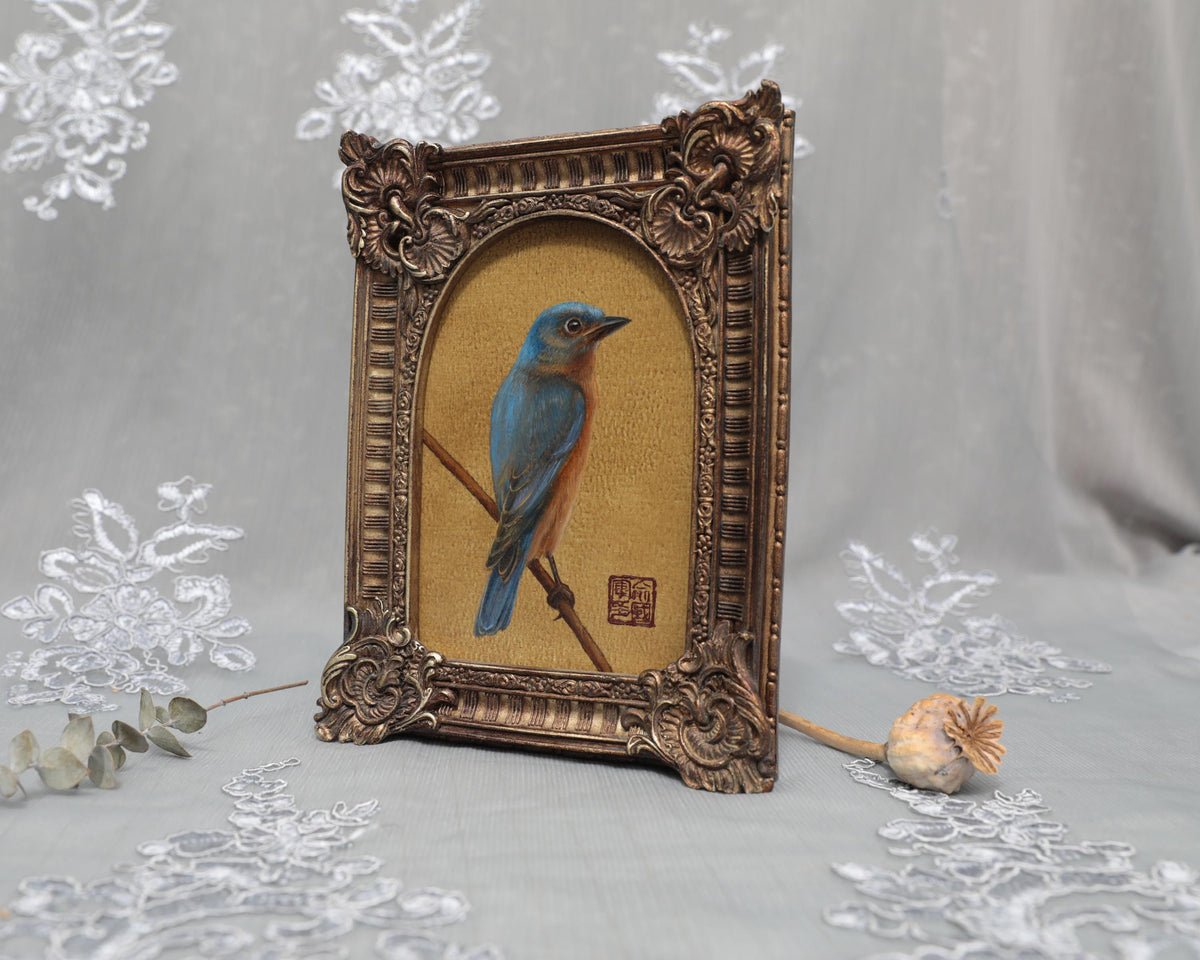Side angle of arch-top bronze frame showing bluebird painting print
