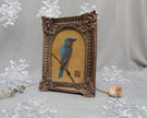 Side angle of arch-top bronze frame showing bluebird painting print