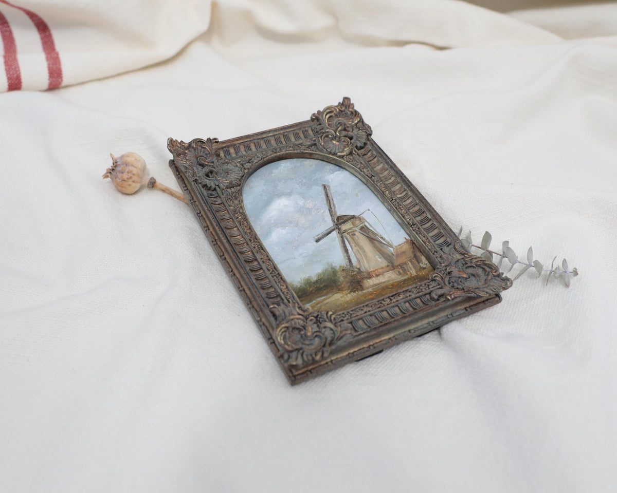 Another different angle view, original countryside landscape painting of a rustic windmill under a cloudy blue sky in an ornate bronze vintage-style frame