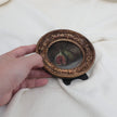 Hand holding round gilt frame with fig still life oil painting for scale comparison 