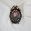 Miniature pink rose oil painting in an oval black and gilt frame with a ribbon bow, another view