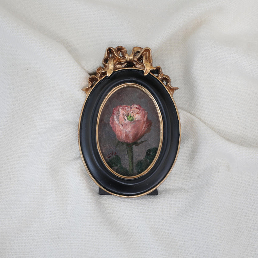 Miniature pink rose oil painting in an oval black and gilt frame with a ribbon bow, another view