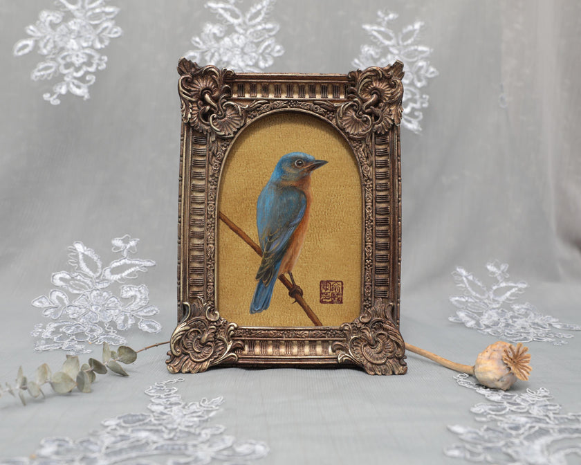 Framed bluebird print with arch-top frame beside dried poppy pod, front view standing