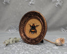 Side angle of framed bumblebee art print in carved bronze frame