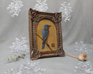 Side angle of arch-top bronze frame showing bluebird painting print