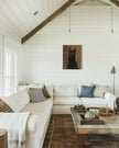 Framed custom black cat oil portrait hanging above a white sectional sofa in a vaulted-ceiling living room