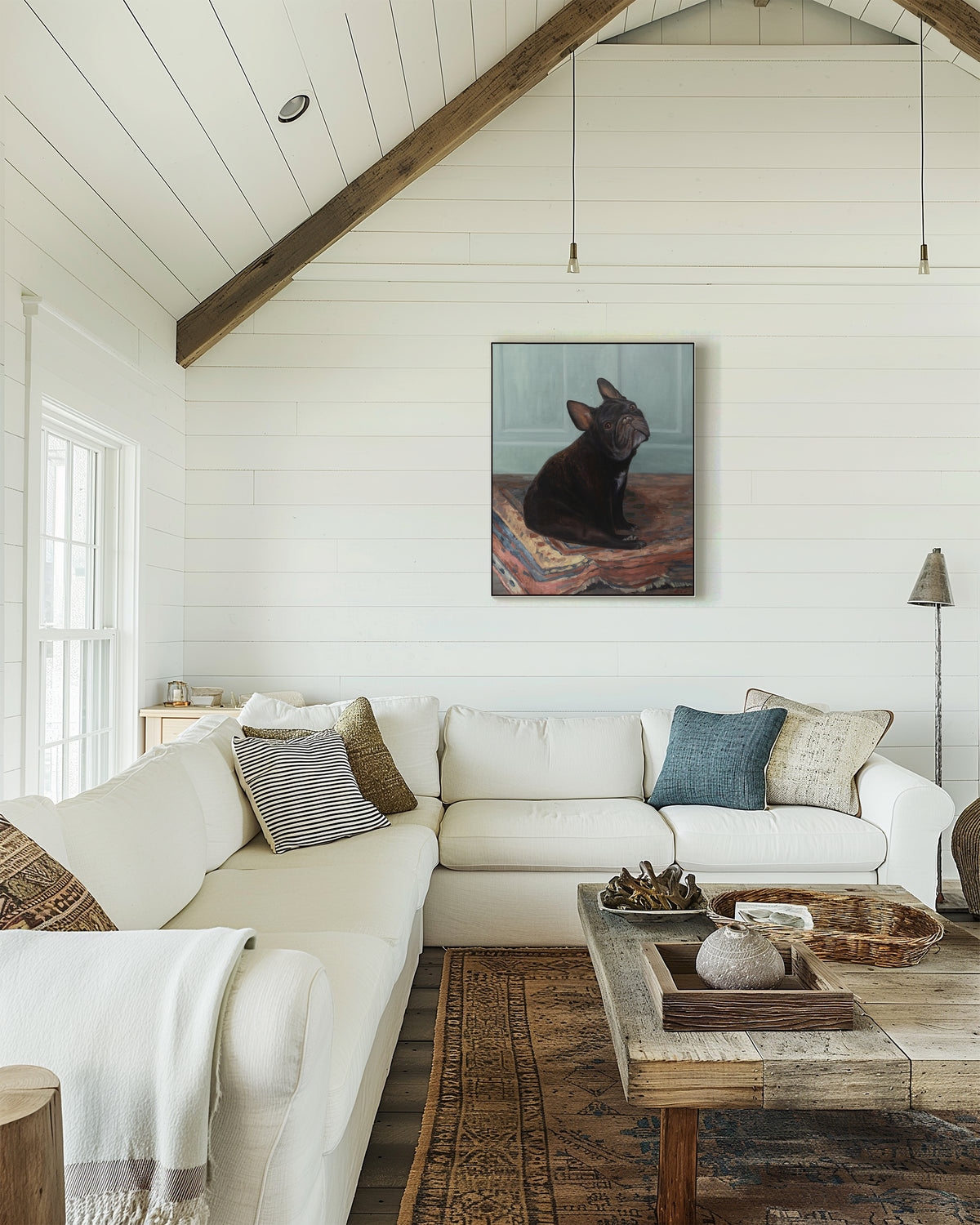 Framed French bulldog oil portrait hanging on a white shiplap wall in a vaulted-ceiling living room