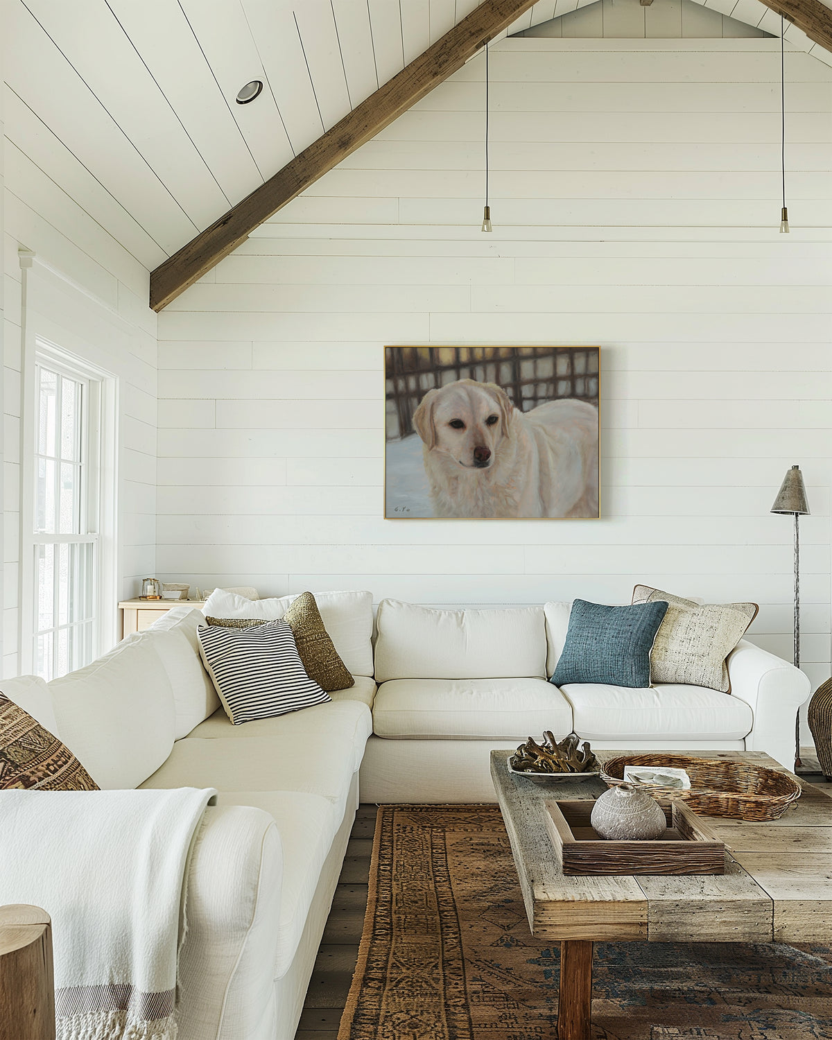 Original oil painting of a retriever dog hanging on a white shiplap wall in a bright, modern living room with a white sectional sofa, wooden ceiling beams, and a rustic coffee table.