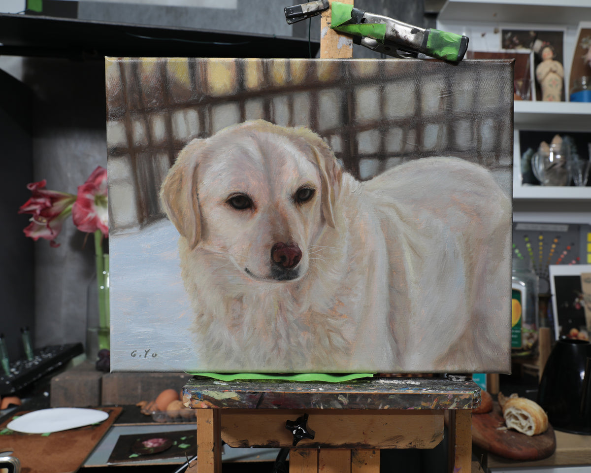 A canvas painting of a golden retriever dog, displayed on an easel in an artist's studio with art supplies and shelves in the background.
