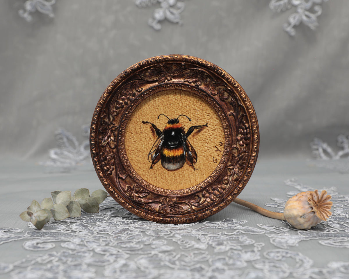 Framed bumblebee art print in ornate bronze frame, standing