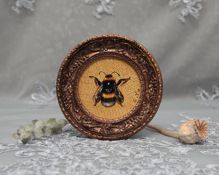 Framed bumblebee art print in ornate bronze frame, standing