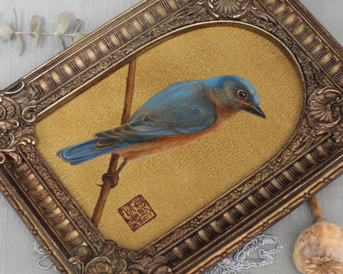 Close-up of bluebird painting print in arch-top bronze frame