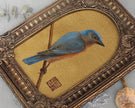 Close-up of bluebird painting print in arch-top bronze frame
