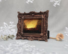 Side angle of framed sunset landscape print in carved bronze frame