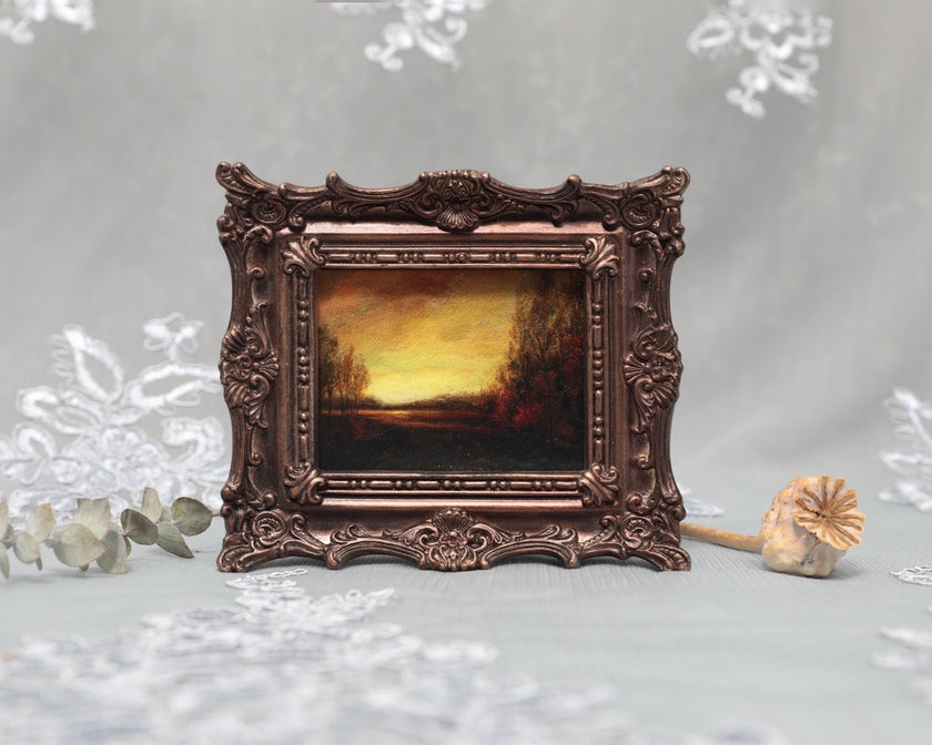 Ornate bronze framed landscape print of golden sunset, standing upright