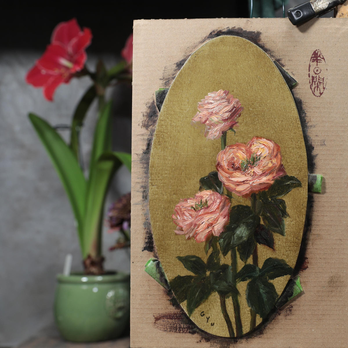 Pink rose oil painting on panel, taped to an easel in the artist's studio