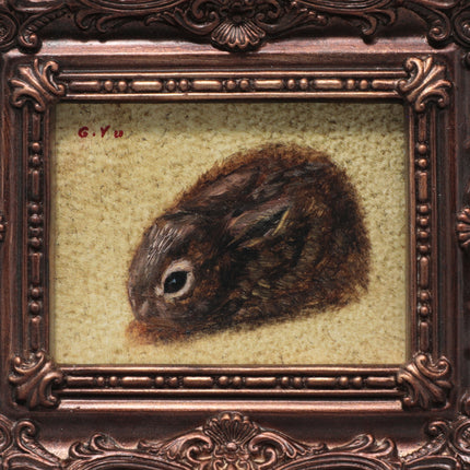 Close up view of a framed artwork showing a detailed brown rabbit illustration on a textured cream background, enclosed in an ornate dark bronze decorative frame.