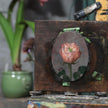 Pink rose miniature oil painting on an oval panel, taped to an easel in the artist's studio