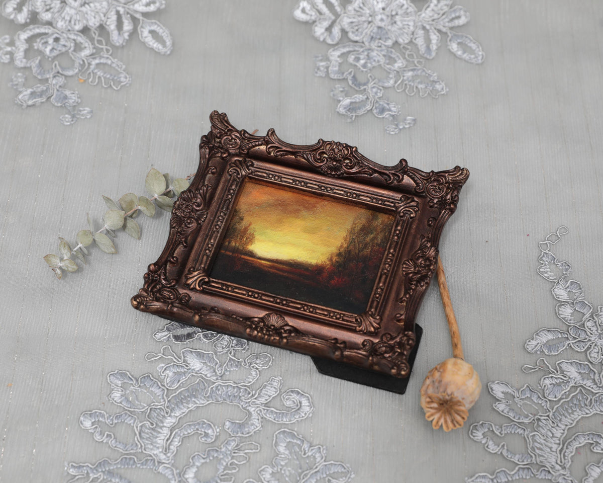 Overhead view of framed sunset landscape print with dried florals