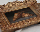 Two croissants oil painting in an antique gold frame, laid flat with soft natural shadow