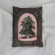 Small oil painting of a green tree on a pink background in an arched ornate vintage-style frame