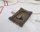 Angled view of an Old Master inspired fig still life painting in an ornate frame beside dried flowers
