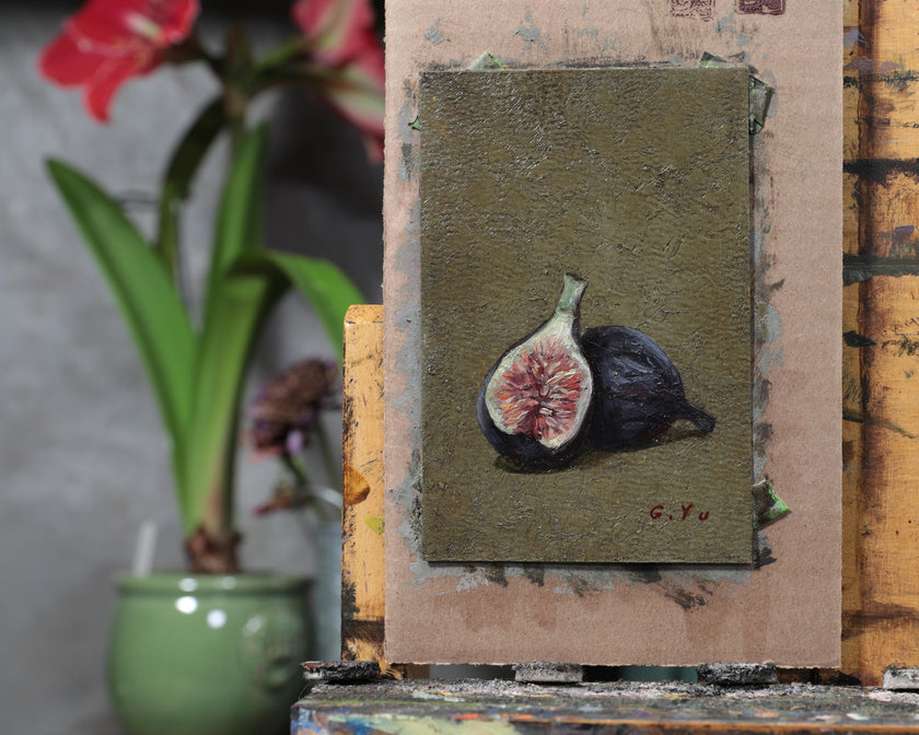 Unframed fig still life oil painting on an easel in the artist's studio beside a potted plant