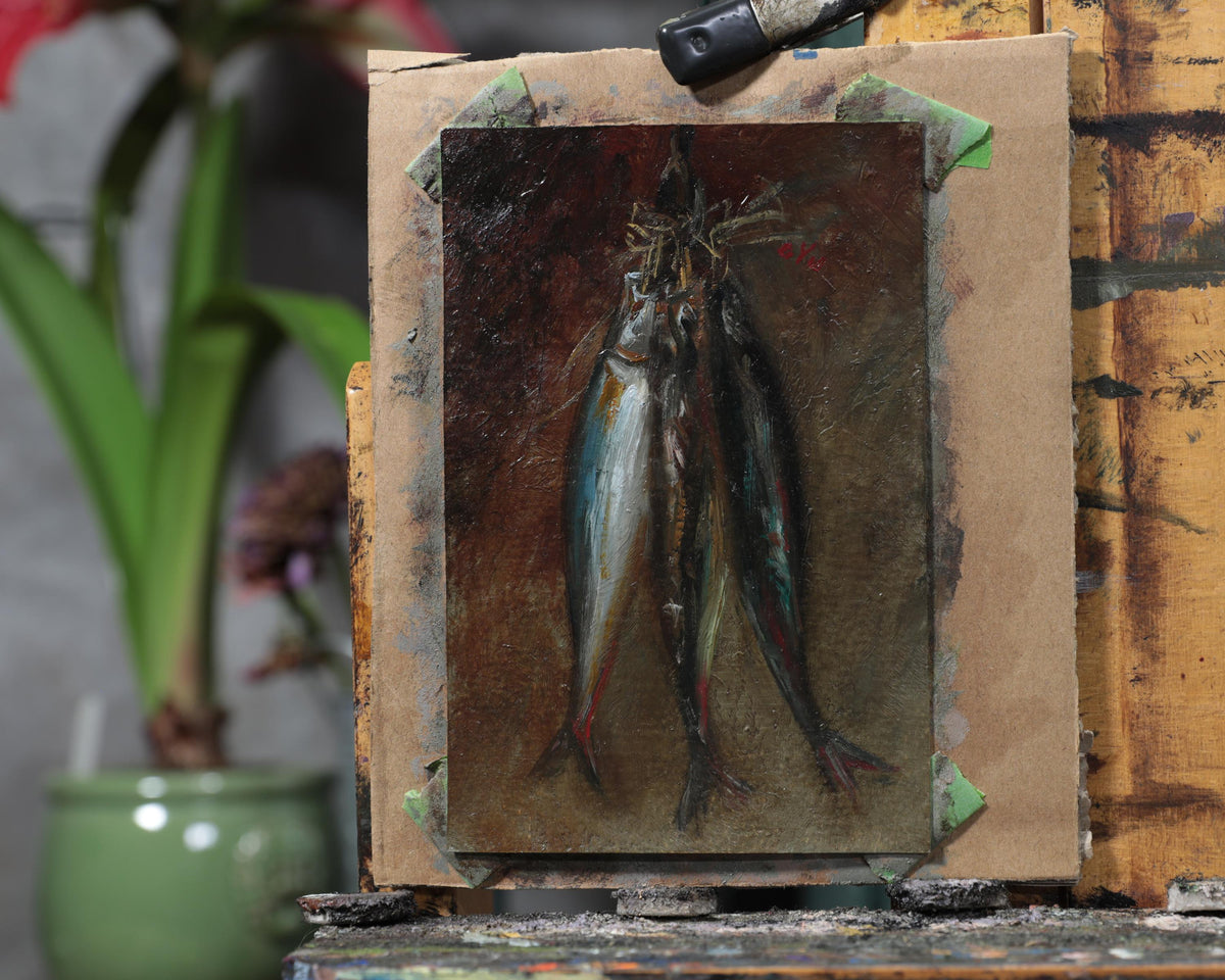 Unframed fish still life oil painting on an easel in the artist's studio