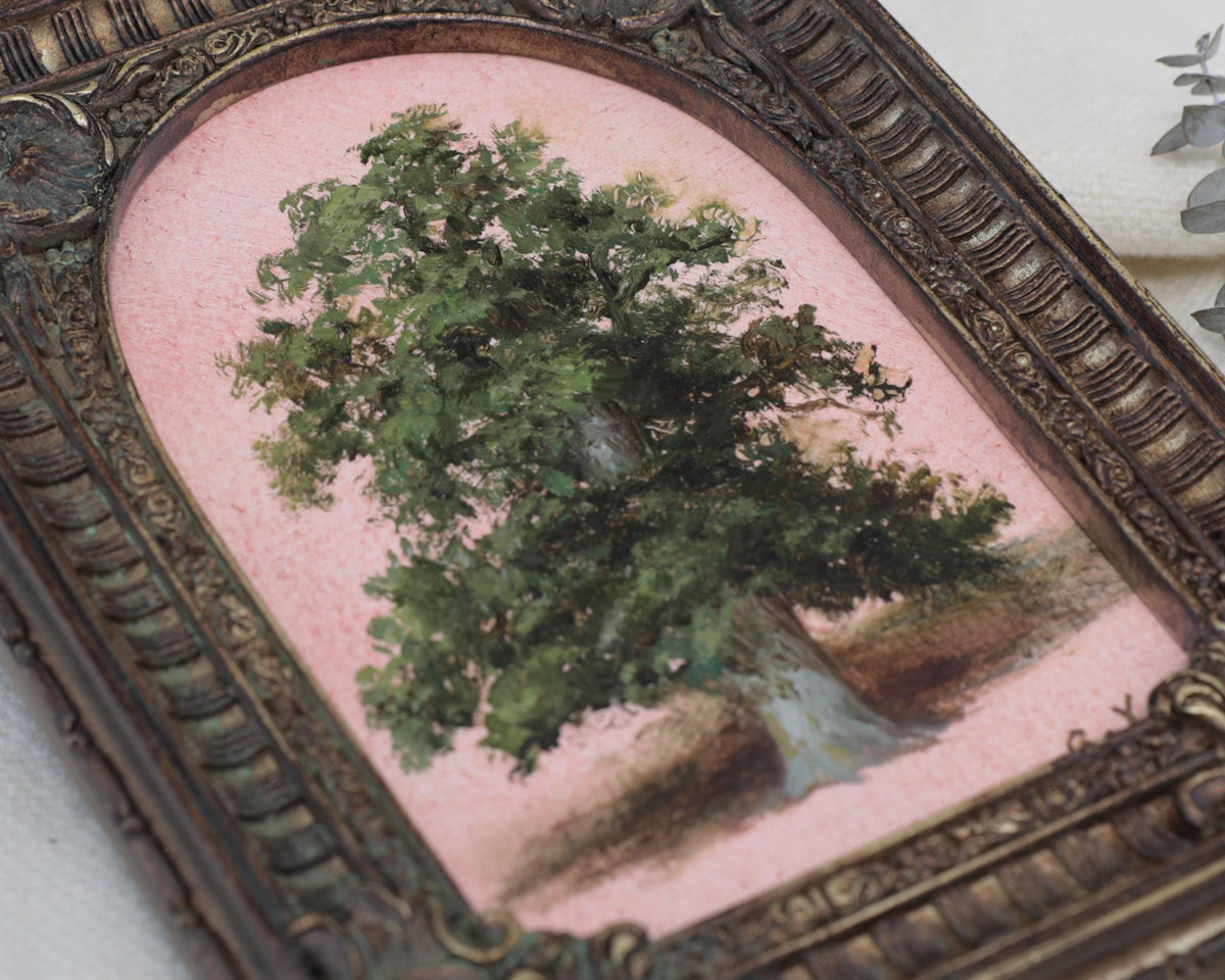 Close-up of an ornate arched frame with shell and scroll corners around a tree oil painting