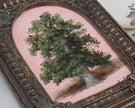 Close-up of an ornate arched frame with shell and scroll corners around a tree oil painting