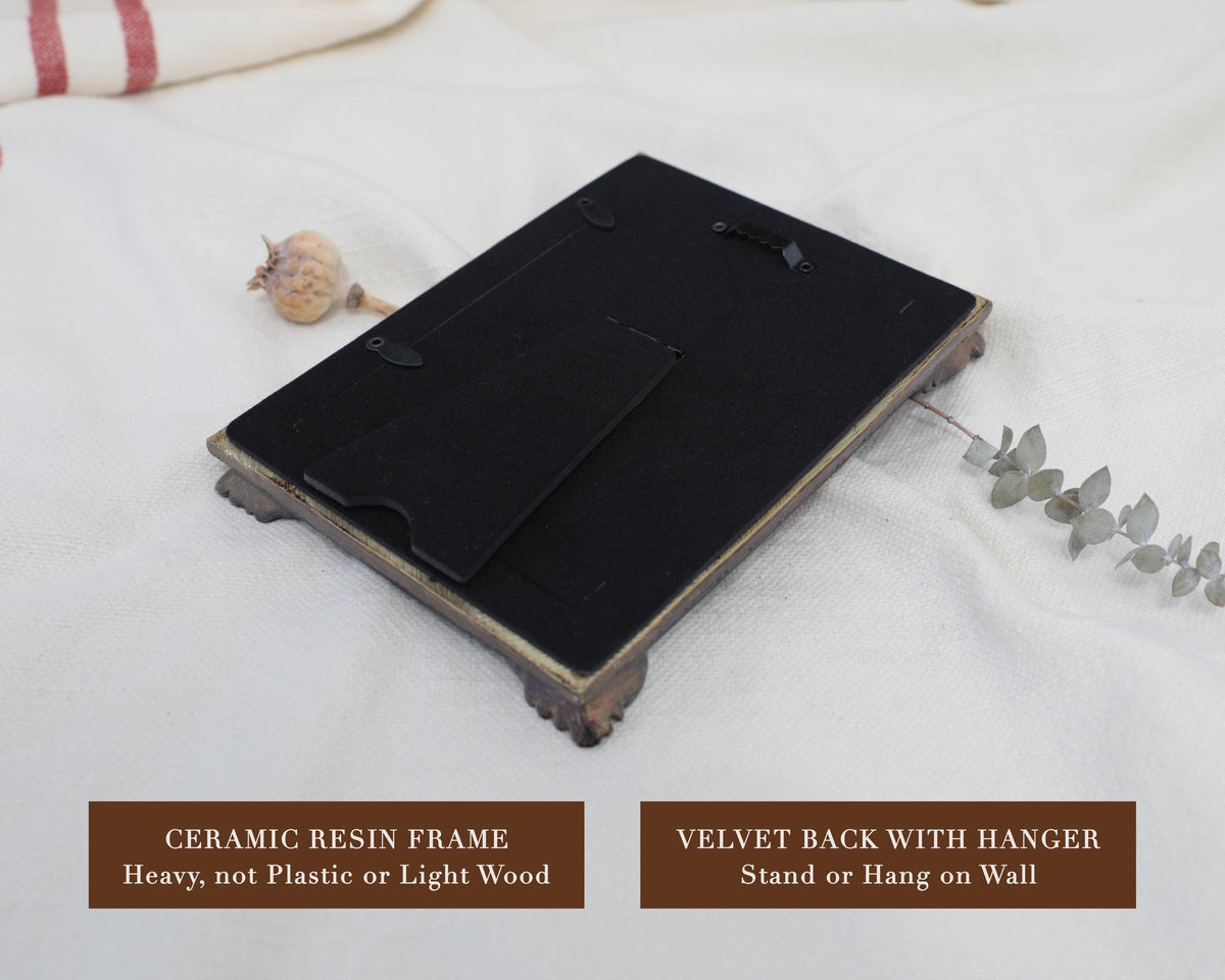 Back of an ornate ceramic resin frame with a black velvet backing and hanger, ready to hang