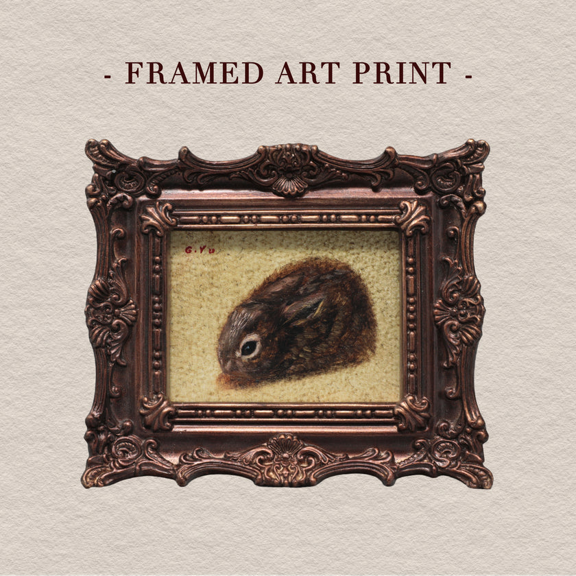 A framed art print featuring a detailed painting of a brown rabbit on a textured cream background, enclosed in an ornate dark brown frame. The text '- FRAMED ART PRINT -' is written above the frame on a textured off-white background.