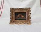 Framed croissant oil painting shown beside striped linen, with the full ornate gold frame visible